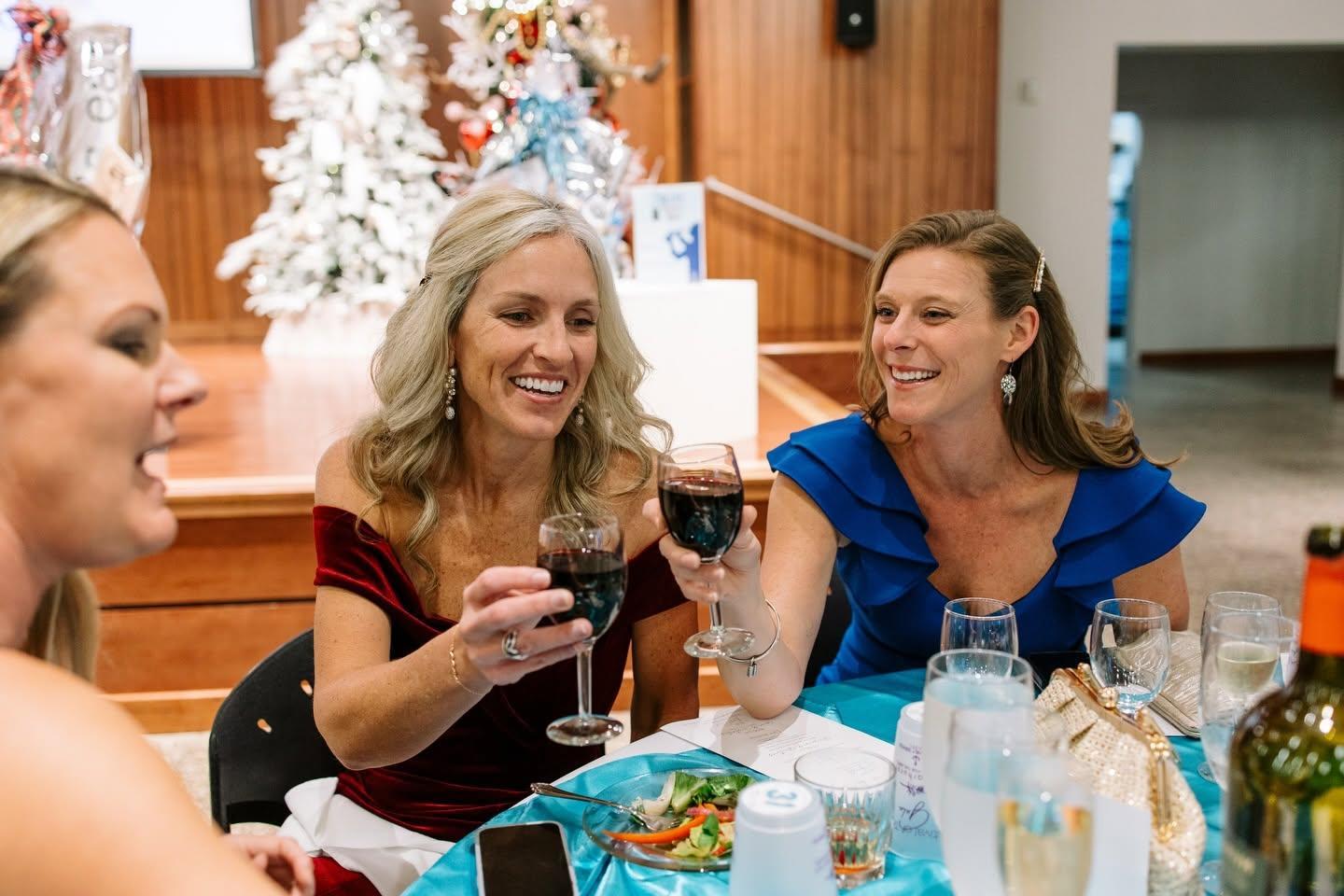 Two women cheers their wine glasses at a gala